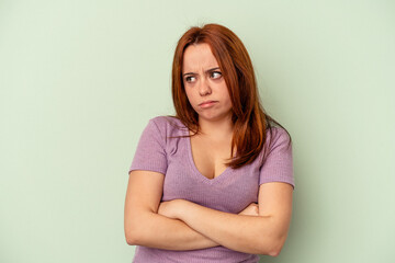 Young caucasian woman isolated on green background tired of a repetitive task.