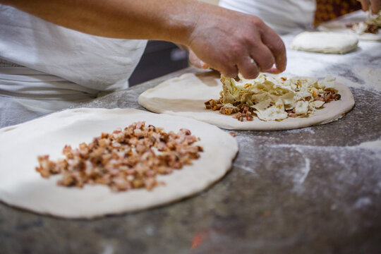 Pizzaiolo mentre prepara due pizze fritte ripiene di mozzarella di bufala e cicoli di maiale
