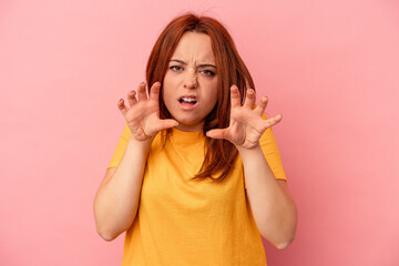 Young caucasian woman isolated on pink background upset screaming with tense hands.