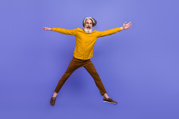 Fototapeta na wymiar Full length body size view of attractive cheery funny gray-haired man jumping having fun isolated over bright violet purple color background