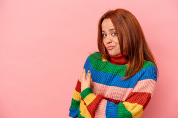 Young caucasian woman isolated on pink background smiling and pointing aside, showing something at blank space.