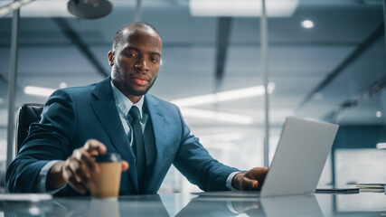 Top Management Modern Office: Successful Black Businessman in Tailored Suit Working on Laptop...