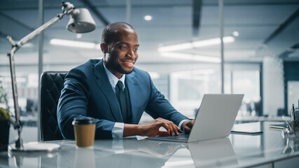 Top Management Modern Office: Successful Black Businessman in Tailored Suit Working on Laptop...