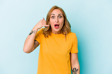 Young caucasian woman isolated on blue background laughing about something, covering mouth with hands.
