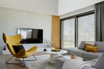 Stylish composition of living room interior with corner beige sofa, yellow armchair, coffee table...