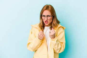 Young caucasian woman isolated on blue background showing fist to camera, aggressive facial...
