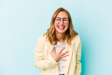 Fototapeta premium Young caucasian woman isolated on blue background laughs out loudly keeping hand on chest.