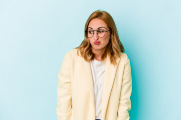 Obraz premium Young caucasian woman isolated on blue background shrugs shoulders and open eyes confused.