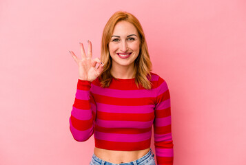 Young caucasian woman isolated on pink background cheerful and confident showing ok gesture.