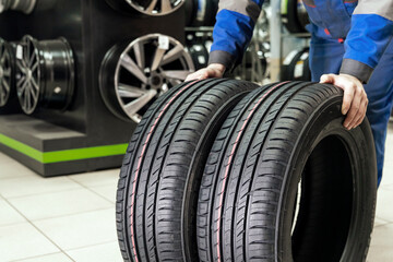 Fototapeta premium the seller rolls a pair of new tires for the season to the store's exit. buying new wheels - road safety