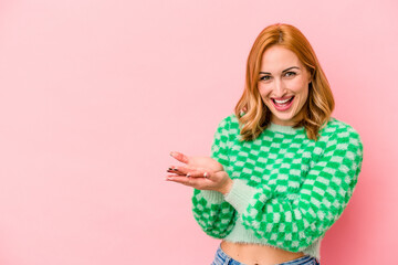 Young caucasian woman isolated on pink background holding a copy space on a palm.