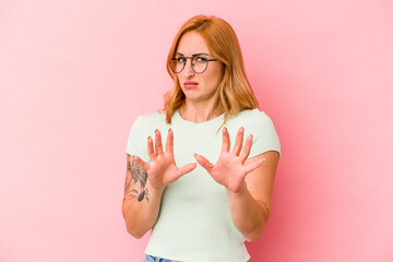 Young caucasian woman isolated on pink background rejecting someone showing a gesture of disgust.