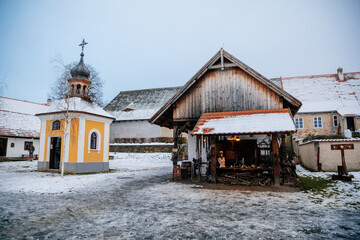 Prerov nad Labem, Czech Republic, 5 December 2021: Traditional village wooden house in winter, historic country-style architecture, Municipal Belfry small church, Polabi open-air ethnographic museum