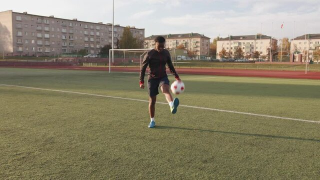 Young black girl training at the city stadium and practicing ball possession technique soccer dribbling