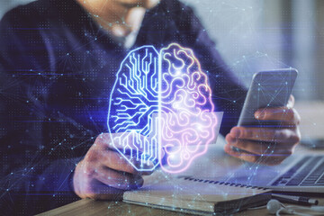 Double exposure of man's hand holding and using a digital device and brain hologram drawing. Data...