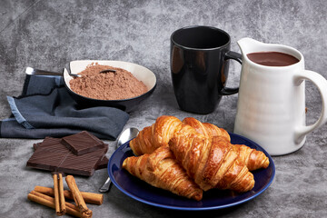 Pitcher of hot chocolate along with delicious croissants and various ingredients