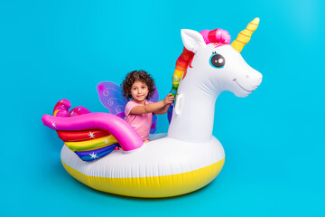 Portrait of attractive carefree cheerful girl riding air horse isolated over vibrant blue color...