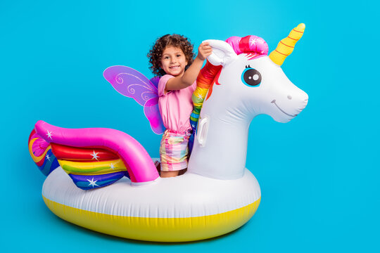 Portrait of attractive cheerful funky girl lying hugging air horse having fun isolated over bright blue color background