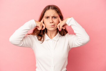 Little caucasian girl isolated on pink background focused on a task, keeping forefingers pointing head.