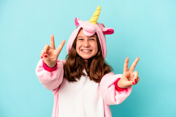 Little caucasian girl wearing a unicorn pajama isolated on pink background © Asier