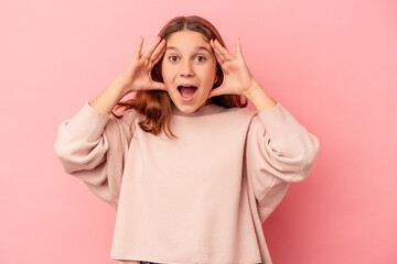 Little caucasian girl isolated on pink background receiving a pleasant surprise, excited and...