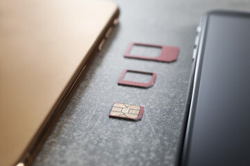 SIM card and mobile phones on grey table, closeup
