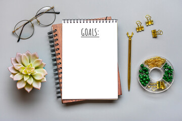 Notepad, homeplant, glasses, pen on gray background Financial planning, goals for New Year concept Top view Flat lay Finance training and strategies Copy space