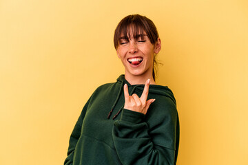 Young Argentinian woman isolated on yellow background showing rock gesture with fingers