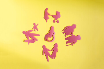 The concept of the relationship between society and people with disabilities. Cardboard figures of different people on a yellow background