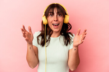 Young Argentinian woman listening to music isolated on pink background receiving a pleasant...