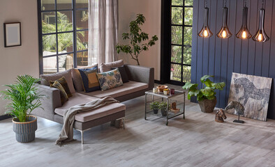 Modern grey sofa in front of the garden view and wooden background wall, lamp vase of plant and middle table, home design.