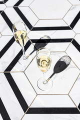Champagne flutes on white and black tiles in direct light