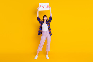 Full length body size view of pretty amazed girl holding board sale wow pout lips isolated over bright yellow color background