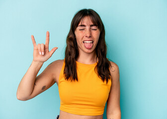 Fototapeta premium Young Argentinian woman isolated on blue background showing rock gesture with fingers
