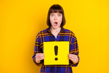 Portrait of attractive amazed girl holding yellow card sign isolated over bright yellow color background