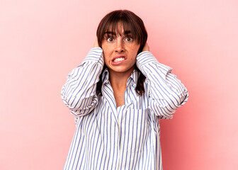 Young Argentinian woman isolated on pink background screaming with rage.