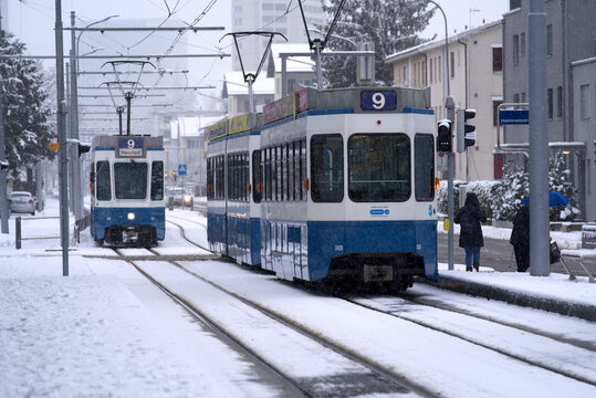 Two number nine trams crossing at tram station on a snowy winter day. Photo taken December 10th, 2021, Zurich, Switzerland.