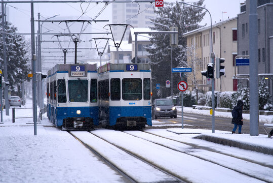 Two number nine trams crossing at tram station on a snowy winter day. Photo taken December 10th, 2021, Zurich, Switzerland.