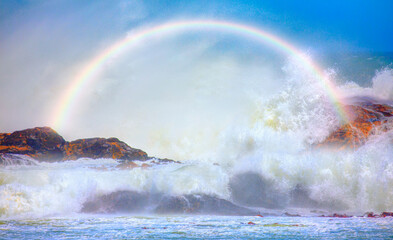 Long strong sea waves with rainbow reflection on a windy day