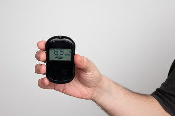 A man suffering from diabetes mellitus shows a glucometer with the results of high blood sugar...