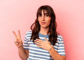 Young Argentinian woman isolated on pink background taking an oath, putting hand on chest.