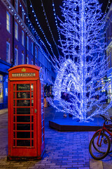 A red telephone booth in front of defocussed, lit christmas decorations in central London for the festive season, England