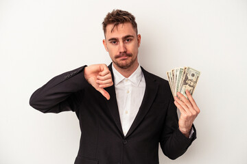 Young caucasian business man holding bank notes isolated on white background showing a dislike gesture, thumbs down. Disagreement concept.