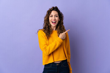 Young caucasian woman isolated on purple background surprised and pointing side