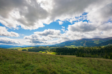 mountain landscape in early autumn. spruce forest on the hills. wonderful nature scenery in dappled light. clouds on the sky