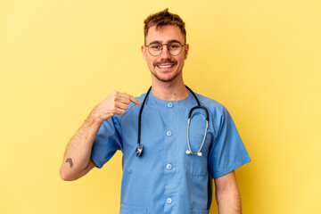 Young nurse caucasian man isolated on yellow background person pointing by hand to a shirt copy space, proud and confident