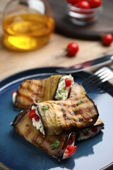 Delicious baked eggplant rolls with cheese, tomatoes and microgreens on plate, closeup