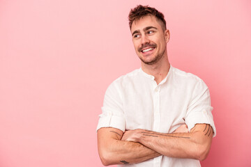 Young caucasian man isolated on pink background smiling confident with crossed arms.