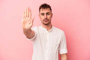 Fototapeta premium Young caucasian man isolated on pink background standing with outstretched hand showing stop sign, preventing you.