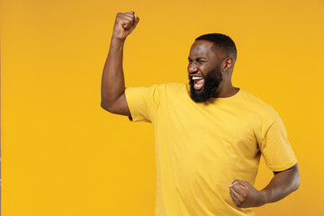 Young exultant happy black man 20s in bright casual t-shirt doing winner gesture celebrate...